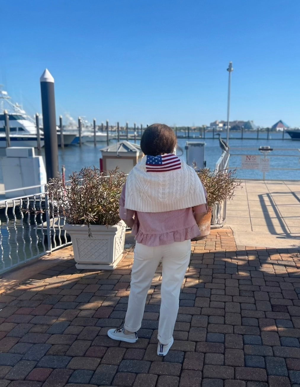 Person standing by a dock with boats and a clear blue sky