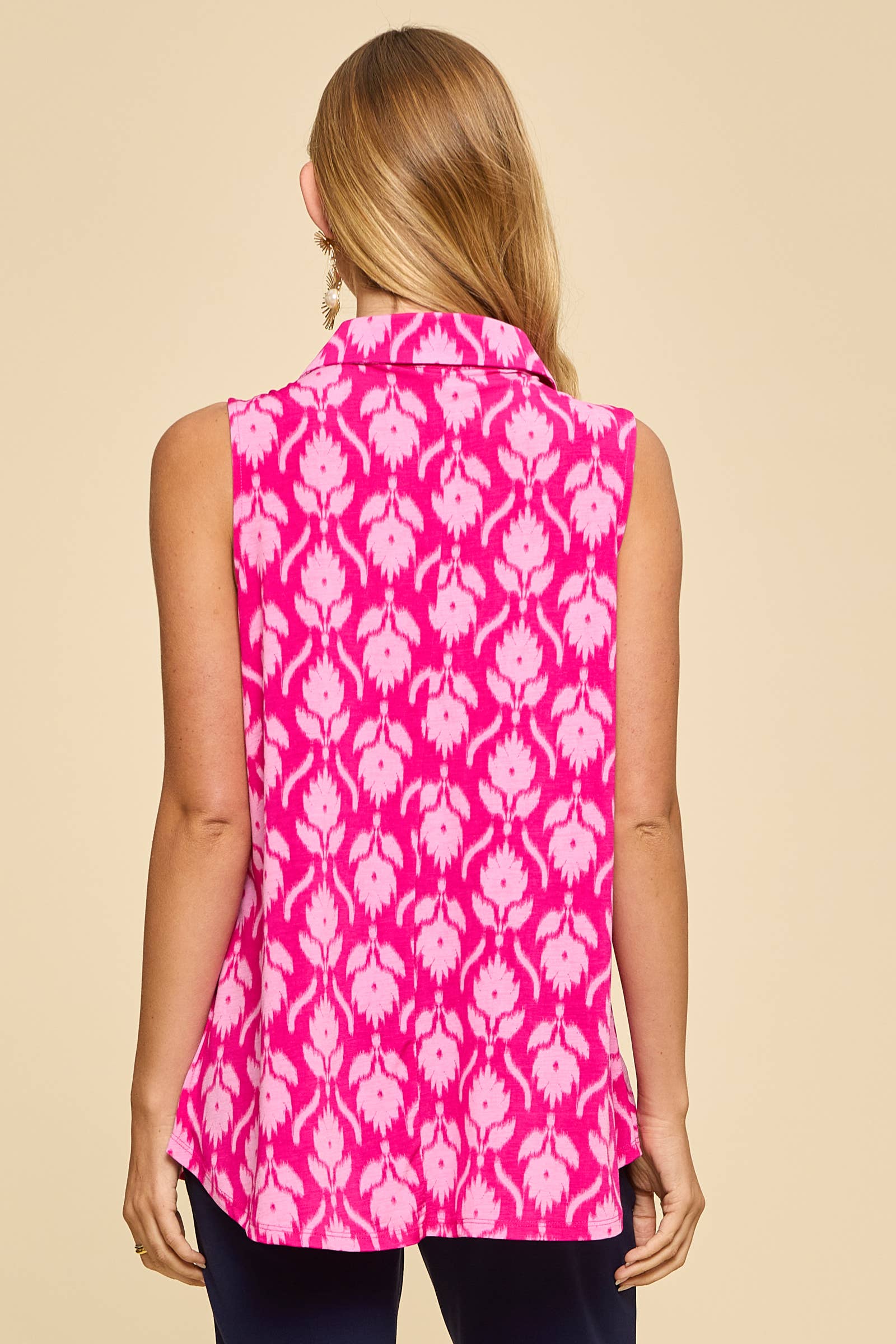 Woman wearing polished sleeveless collared tank top in vibrant fuchsia ikat print with gold buttons