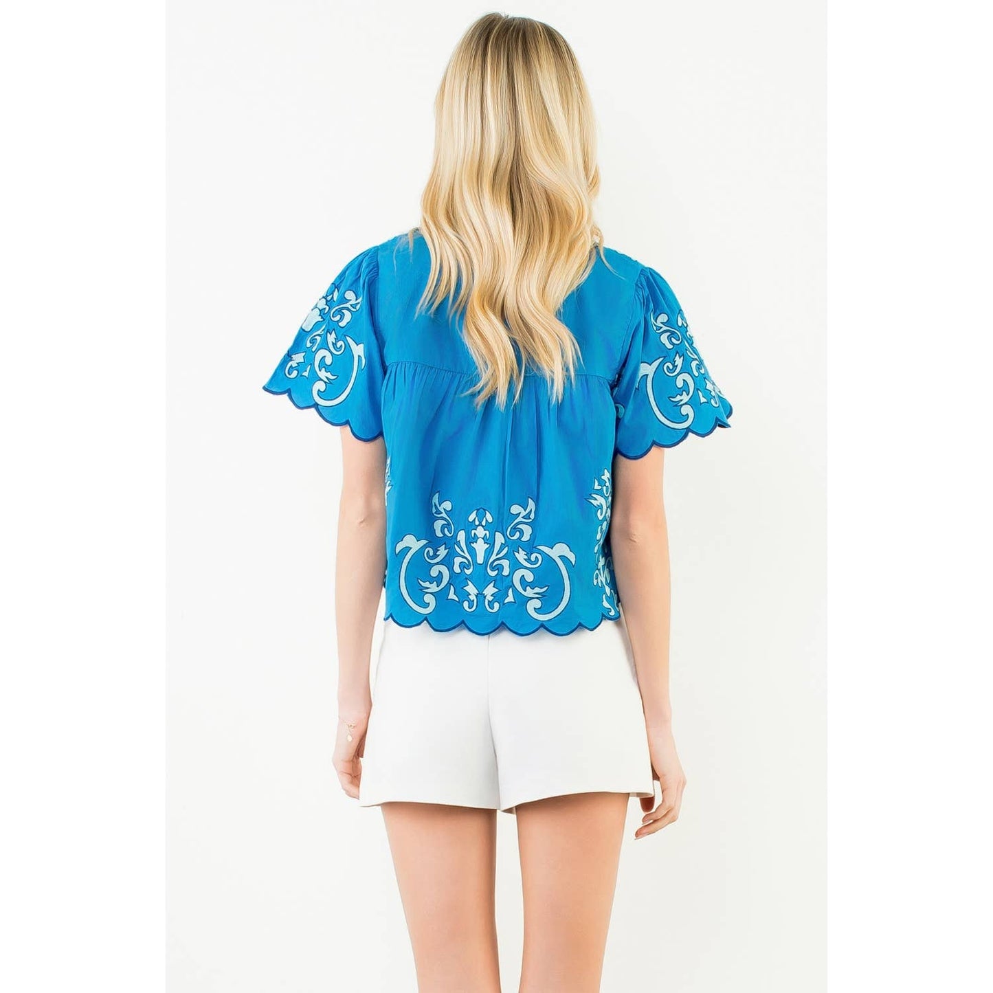 Woman wearing the Harbor Breeze Top in rich cobalt blue with white scrollwork embroidery and scalloped edges